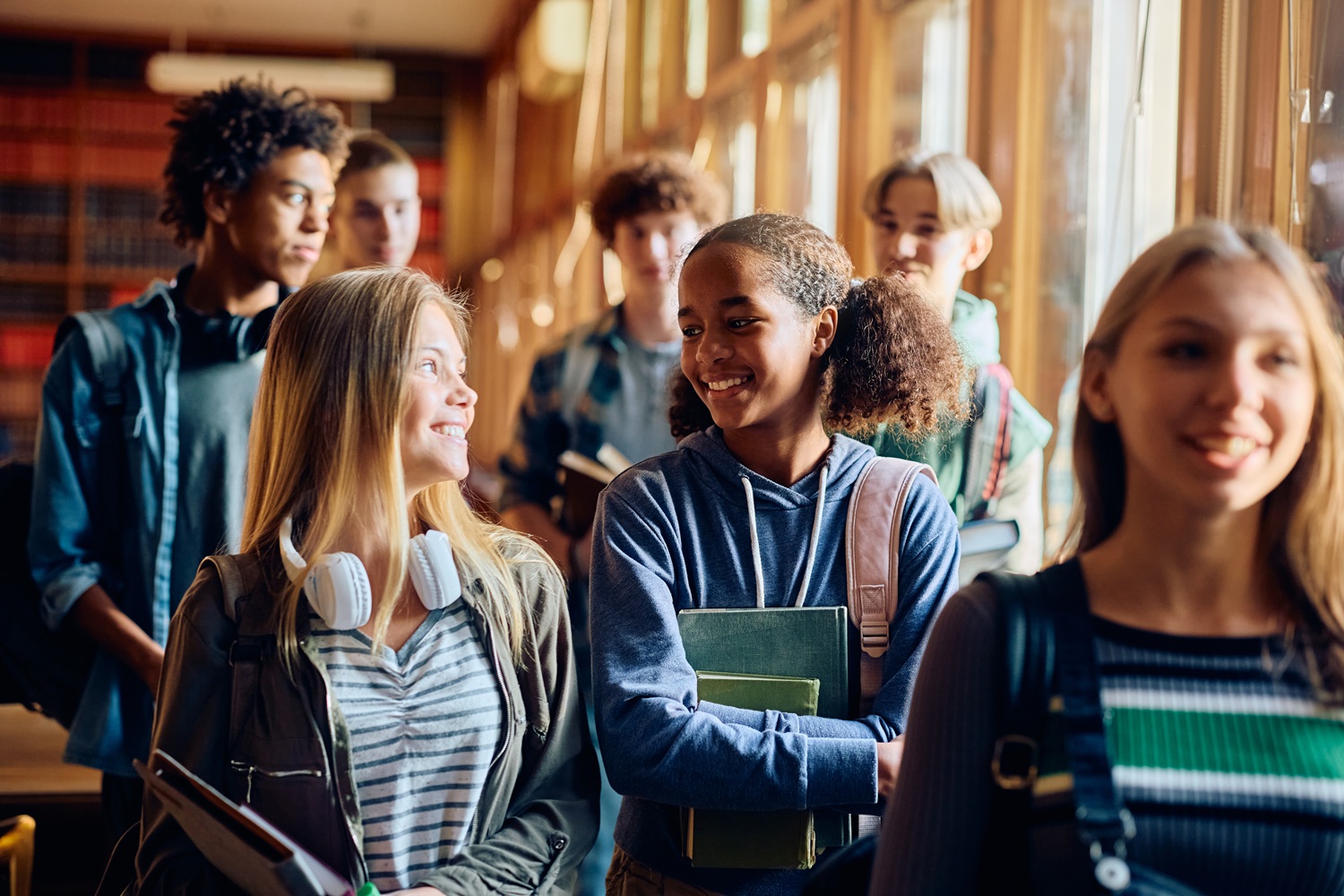 Multiracial group of happy high school students talking after the class.